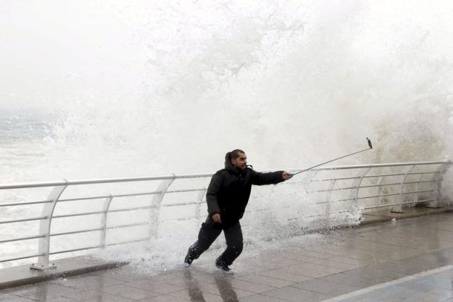 File photo of a man taking a selfie by a crashing wave on Beirut's Corniche, a seaside promenade, as high winds sweep through Lebanon during a storm